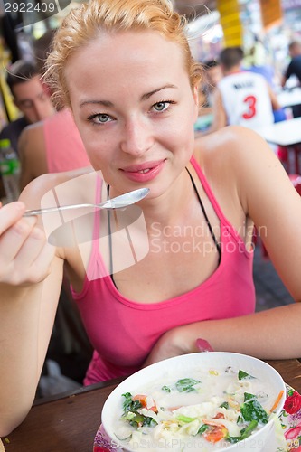 Image of Traveler eating traditional thai Tom Yum soup.