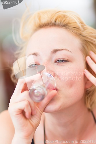 Image of Lady having a shot of spirit drink.