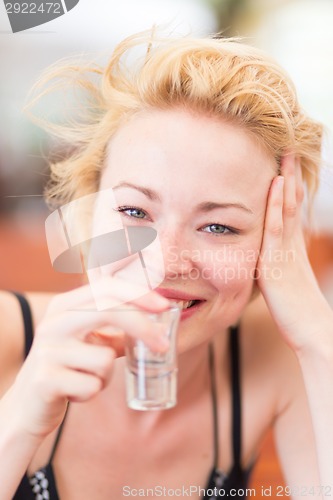 Image of Lady having a shot of spirit drink.