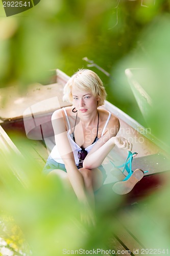 Image of Woman relaxing on the vintage wooden boat.