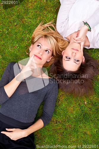 Image of Two thoughtful girls lying in the grass