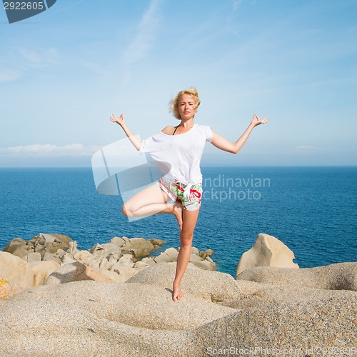 Image of Woman practicing yoga at the beach.