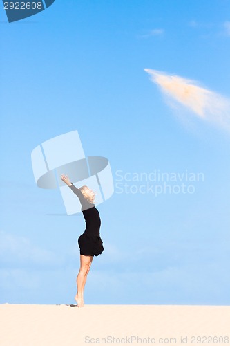 Image of Playful girl throwing sand in the air.