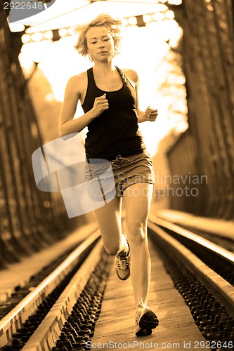 Image of Active female athlete running on railaway tracks.