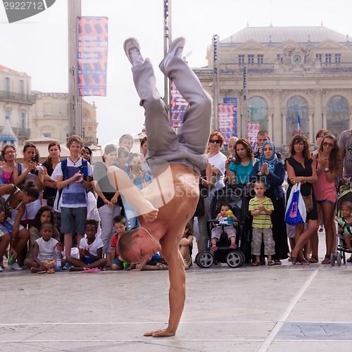 Image of Street performer breakdancing in front of the random crowd.