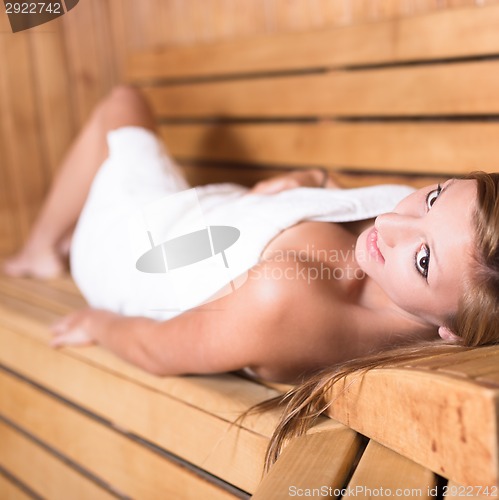 Image of Lady relaxing in traditional wooden sauna.