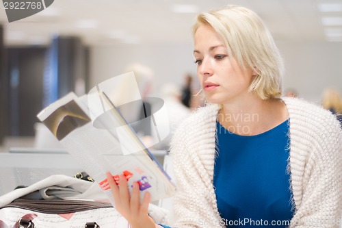 Image of Woman reading a magazine while waiting.