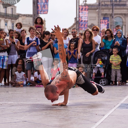 Image of Street performer breakdancing in front of the random crowd.