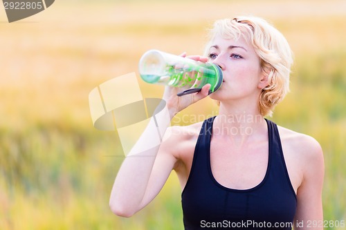 Image of Portrait of woman drinking water outdoor.