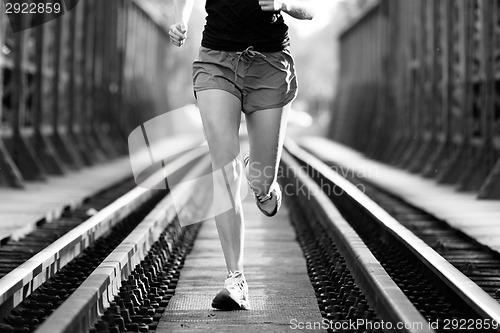 Image of Active female athlete running on railaway tracks.