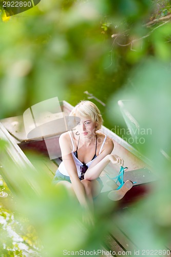 Image of Woman relaxing on the vintage wooden boat.