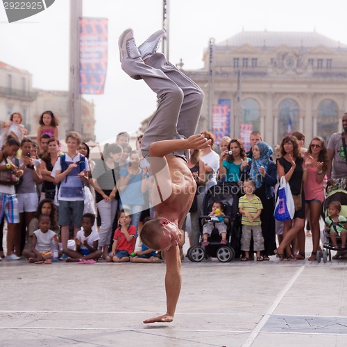 Image of Street performer breakdancing in front of the random crowd.