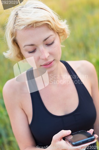 Image of Sporty lady outdoor with a smart phone