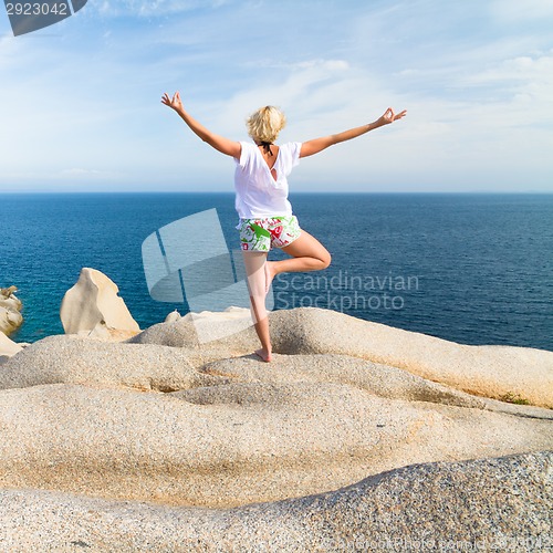 Image of Woman practicing yoga at the beach.