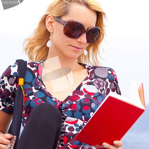 Image of Attractive young lady reading a book.