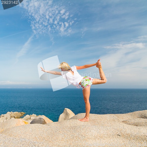 Image of Woman practicing yoga at the beach.
