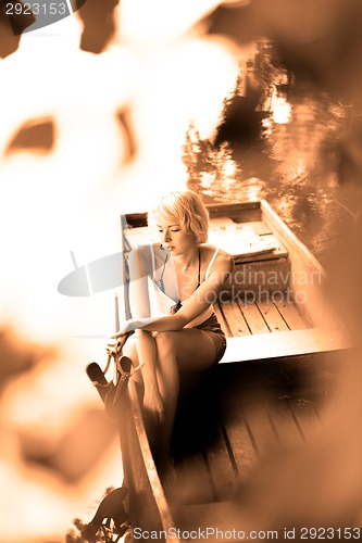 Image of Woman relaxing on the vintage wooden boat.