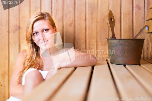 Image of Lady relaxing in traditional wooden sauna.