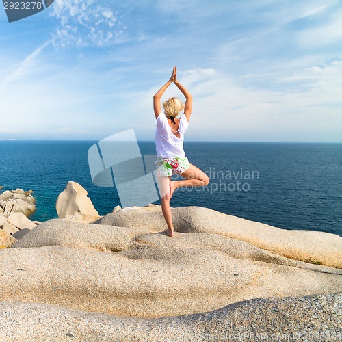 Image of Woman practicing yoga at the beach.