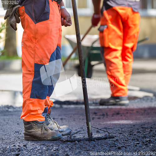 Image of Asphalt surfacing manual labor.