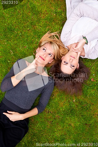 Image of Two thoughtful girls lying in the grass