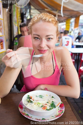 Image of Traveler eating traditional thai Tom Yum soup.