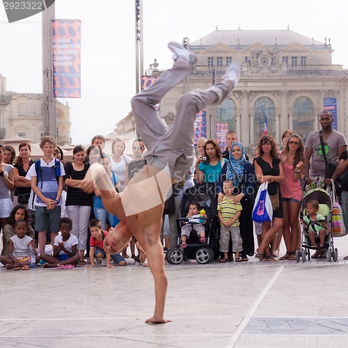 Image of Street performer breakdancing in front of the random crowd.