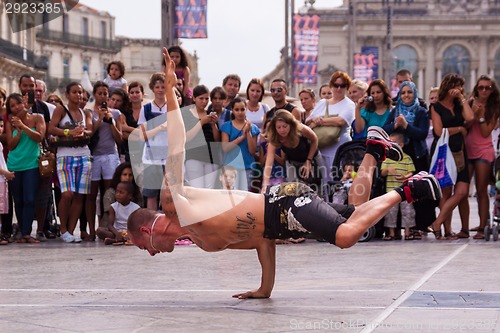 Image of Street performer breakdancing in front of the random crowd.