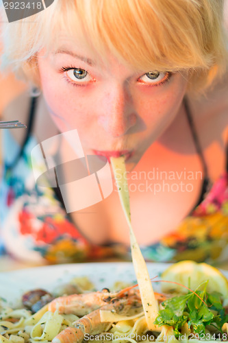 Image of Woman eating seafood noodles.