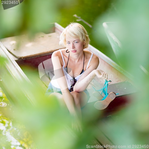 Image of Woman relaxing on the vintage wooden boat.