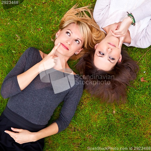 Image of Two thoughtful girls lying in the grass