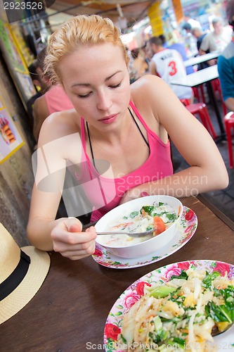 Image of Traveler eating traditional thai Tom Yum soup.