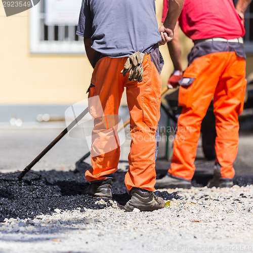 Image of Asphalt surfacing manual labor.