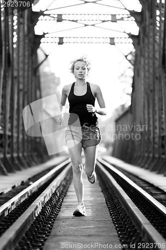 Image of Active female athlete running on railaway tracks.