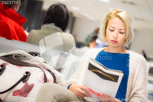 Image of Woman reading a magazine while waiting.