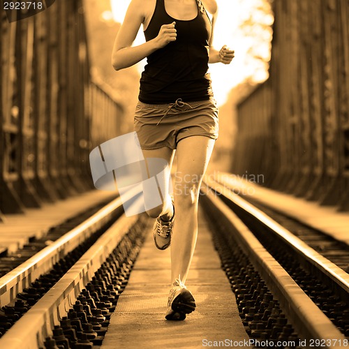 Image of Active female athlete running on railaway tracks.