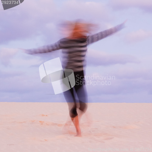 Image of Girl swirling at the sand dune.