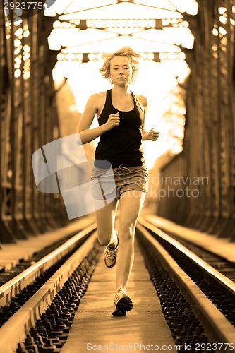 Image of Active female athlete running on railaway tracks.