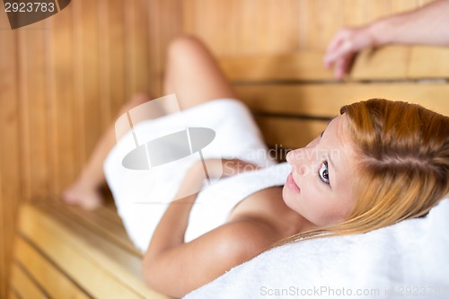 Image of Lady relaxing in traditional wooden Finnish sauna.