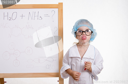 Image of Girl chemist at the blackboard showing tongue