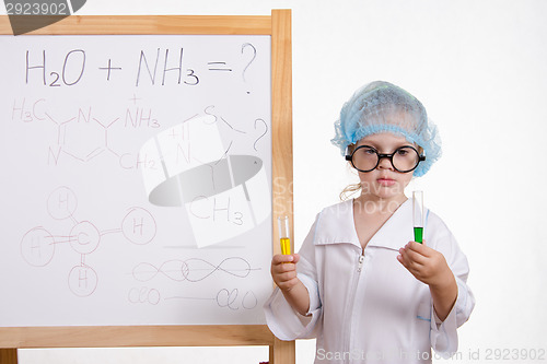 Image of Chemist girl in points and with two tubes at board