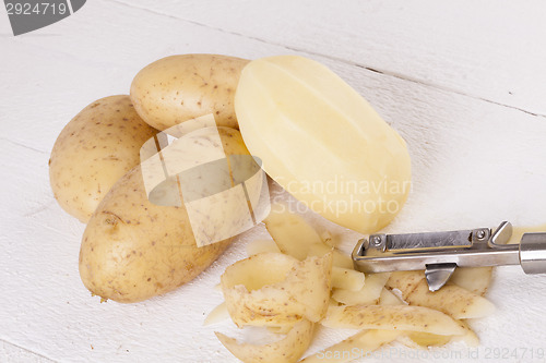 Image of Potatoes with Peeler and Peeled Skin