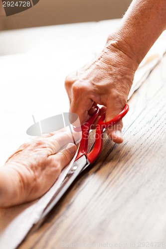 Image of Hand Cutting Cloth with Scissors