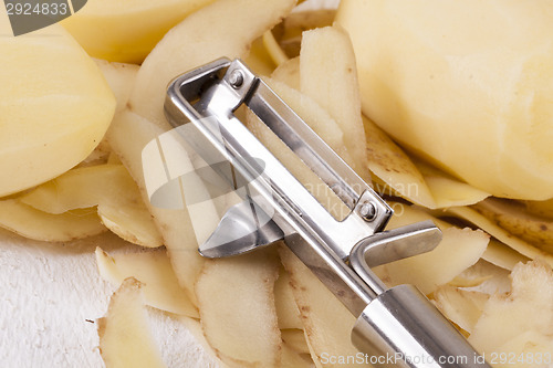 Image of Potatoes with Peeler and Peeled Skin