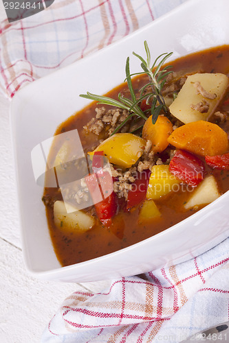Image of Hearty Stew in Bowl and Spoon on Plaid Dish Towel