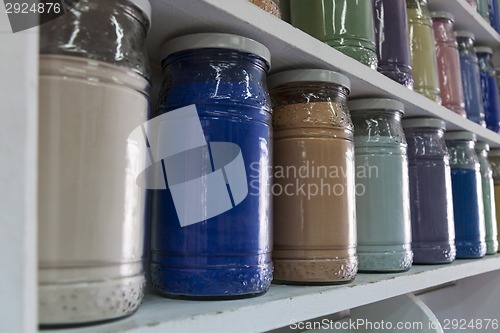 Image of Shelving with glass jars of colorful pigments