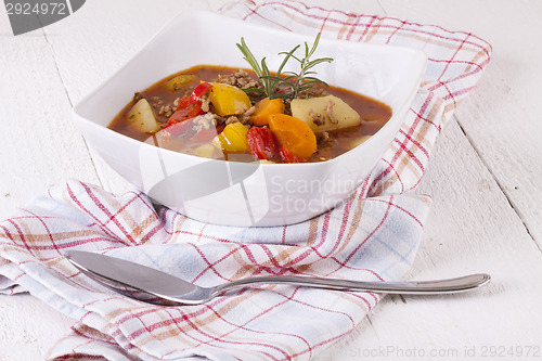 Image of Hearty Stew in Bowl and Spoon on Plaid Dish Towel