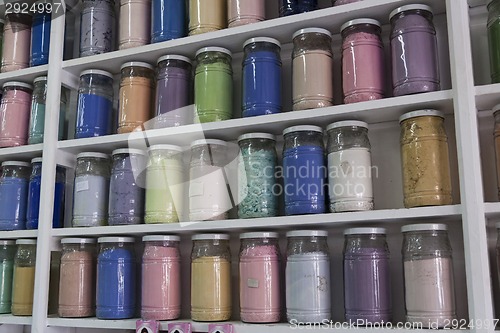 Image of Shelving with glass jars of colorful pigments