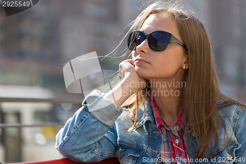 Image of Portrait in profile of a young beautiful pensive girl in sunglas