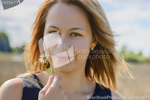 Image of Portrait of young female with camomile